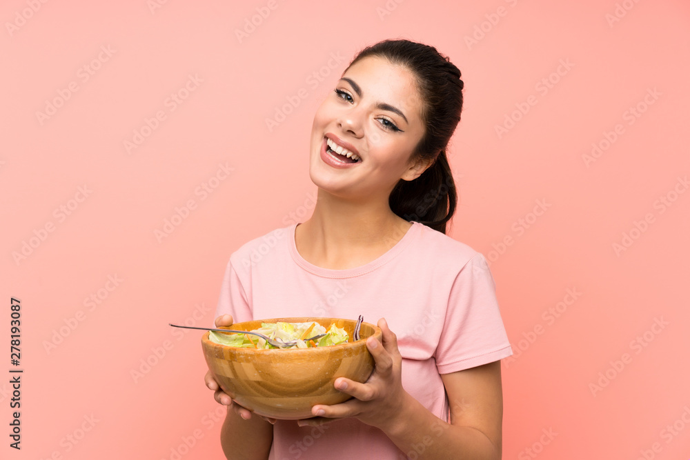 Happy Teenager girl over isolated pink wall with salad Happy Teenager girl over isolated pink wall with salad