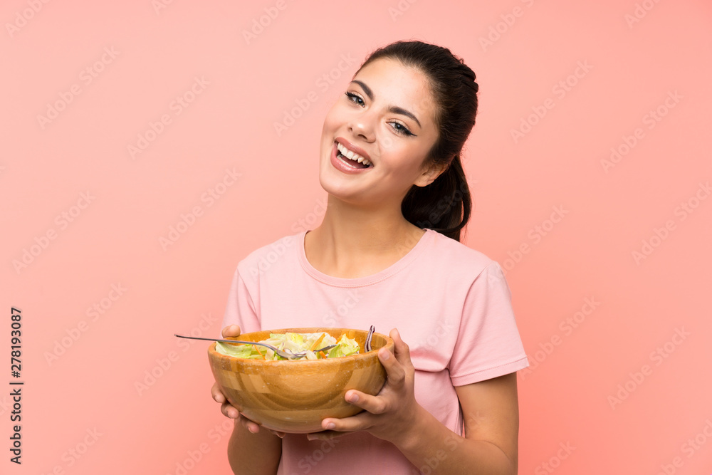 Happy Teenager girl  over isolated pink wall with salad