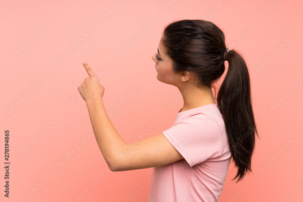 Teenager girl over isolated pink background pointing back with the index finger Teenager girl over isolated pink background pointing back with the index finger