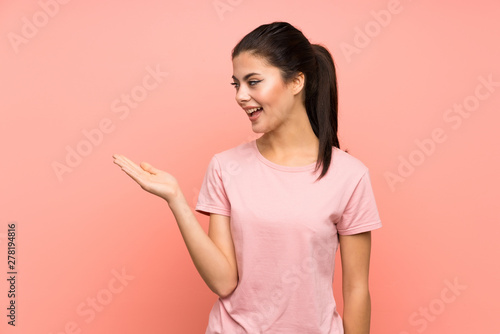Teenager girl over isolated pink background holding copyspace imaginary on the palm © luismolinero