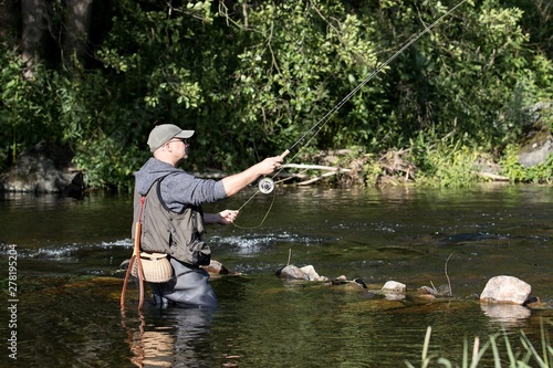 fisherman standing in the river and fly fishing