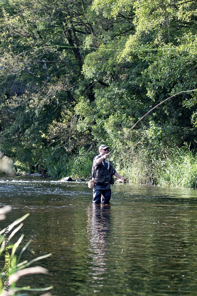 fisherman standing in the river and fly fishing