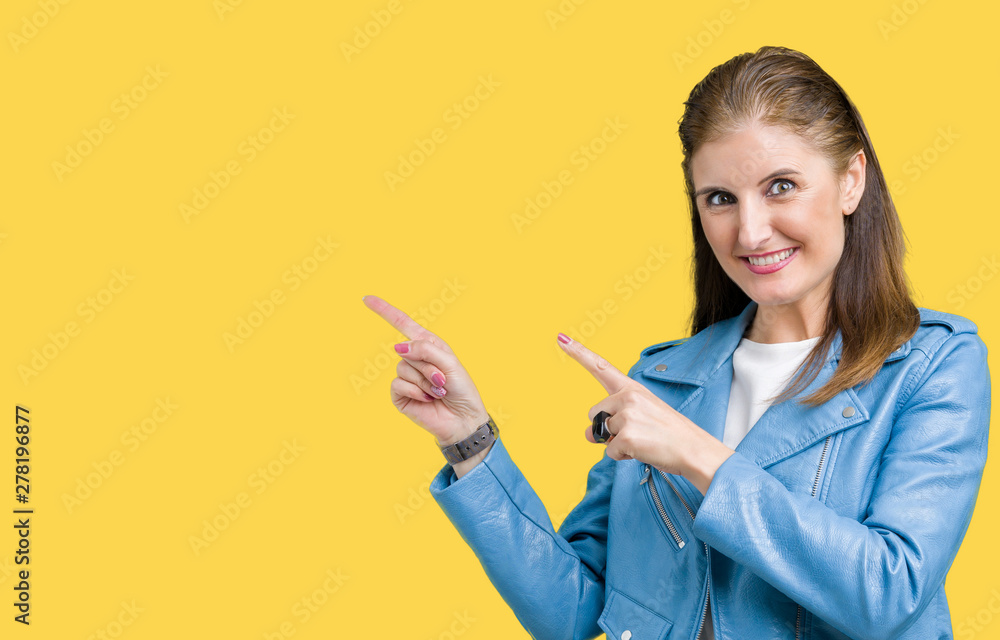Beautiful middle age mature woman wearing fashion leather jacket over isolated background smiling and looking at the camera pointing with two hands and fingers to the side. Beautiful middle age mature woman wearing fashion leather jacket over isolated background smiling and looking at the camera pointing with two hands and fingers to the side.
