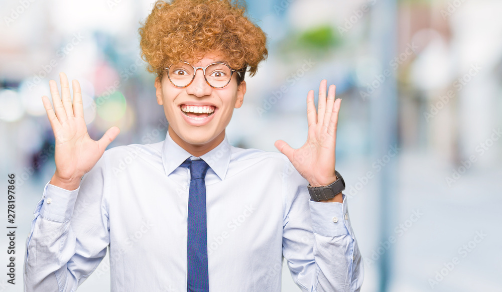 Young handsome business man with afro wearing glasses celebrating crazy and amazed for success with arms raised and open eyes screaming excited. Winner concept Young handsome business man with afro wearing glasses celebrating crazy and amazed for success with arms raised and open eyes screaming excited. Winner concept