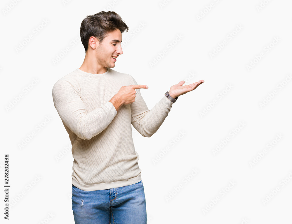 Young handsome man over isolated background amazed and smiling to the camera while presenting with hand and pointing with finger. Young handsome man over isolated background amazed and smiling to the camera while presenting with hand and pointing with finger.