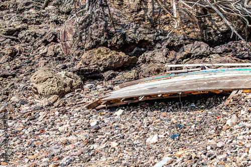 The small fishing boat wreck is broken at a rocky beach.