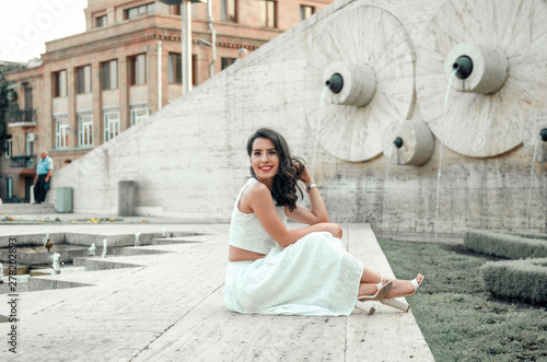 young woman in white dress outside posing and smiling