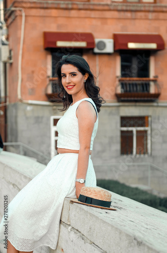 young woman in white dress outside posing and smiling