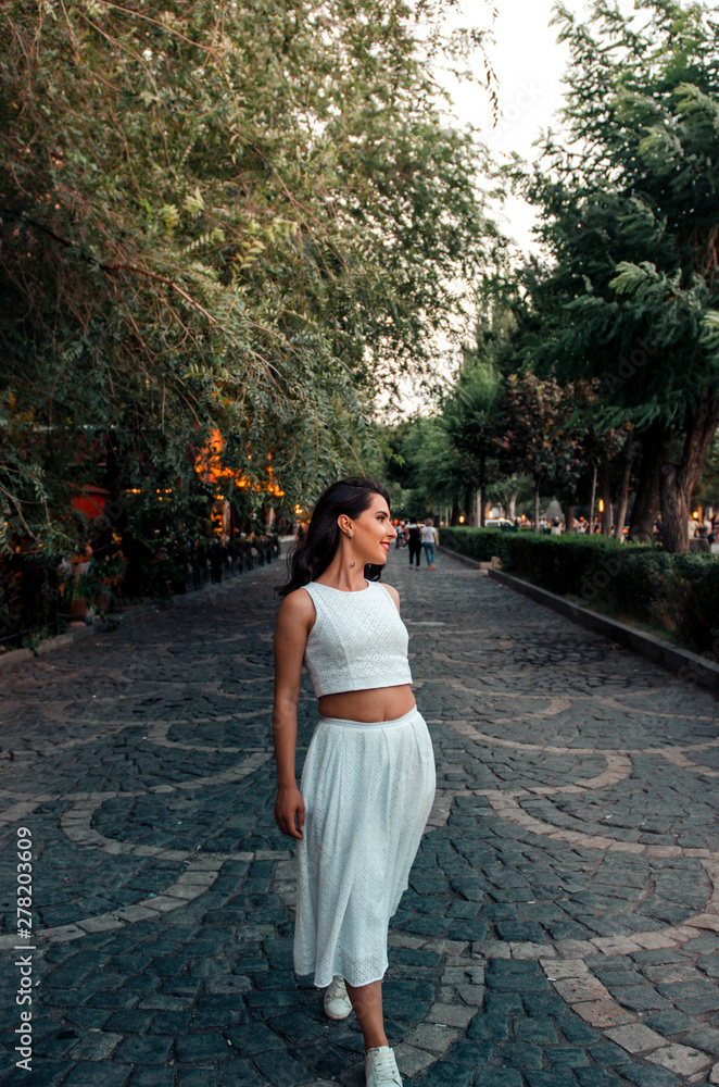 young woman in white dress outside walking and smiling young woman in white dress outside walking and smiling
