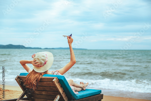 Asian woman with airplane on sea beach