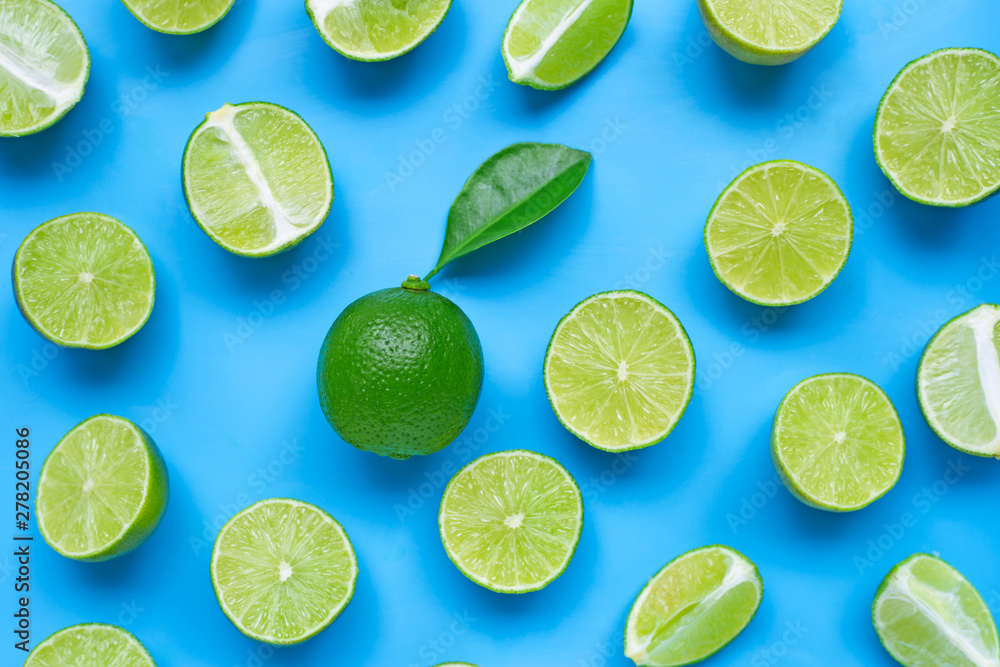 Limes with leaf on blue background. Top view