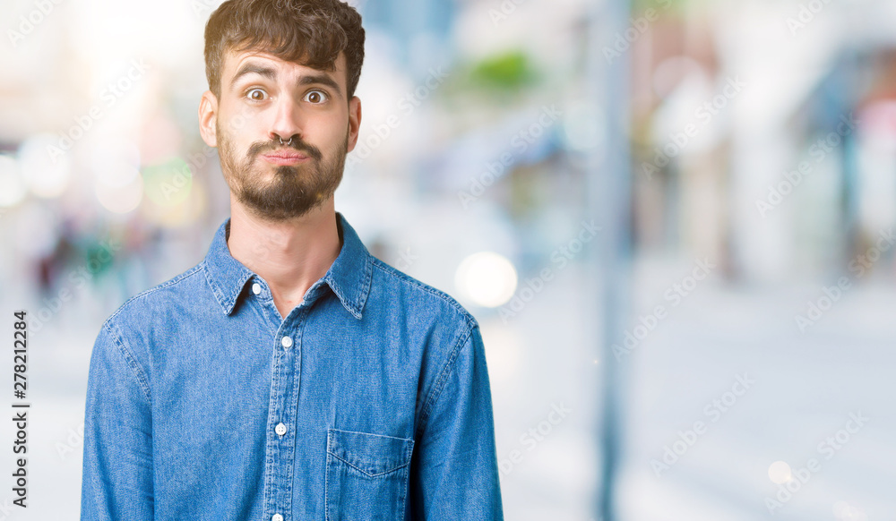 Fototapeta premium Young handsome man over isolated background puffing cheeks with funny face. Mouth inflated with air, crazy expression.