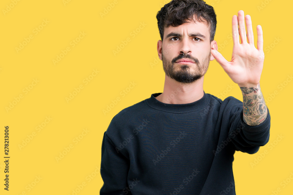 Naklejka premium Young handsome man over isolated background doing stop sing with palm of the hand. Warning expression with negative and serious gesture on the face.