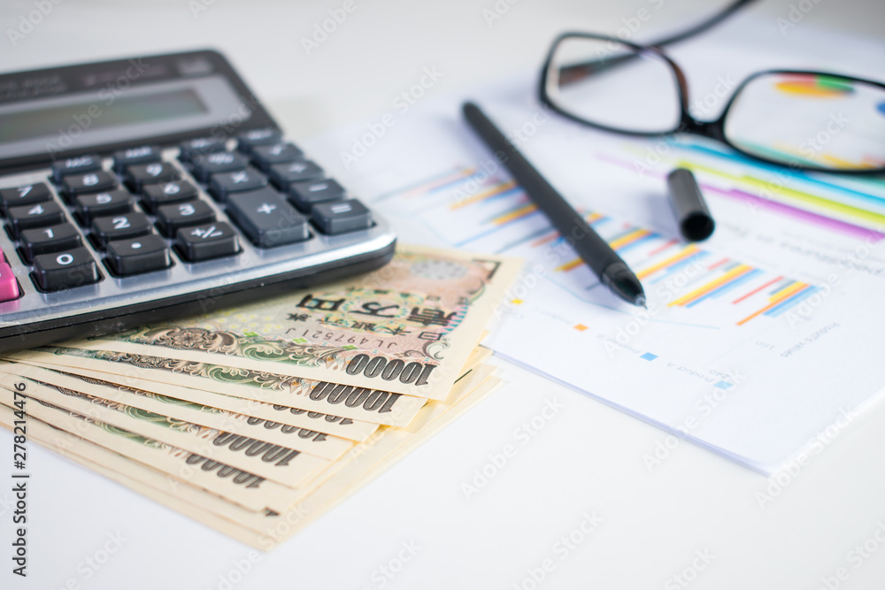 Calculating yen with 10,000 yen bank, calculator, Pen, paper and eyeglasses on white table Calculating yen with 10,000 yen bank, calculator, Pen, paper and eyeglasses on white table