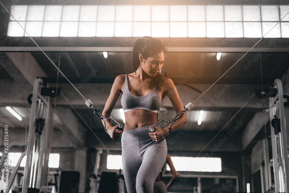 Fototapeta premium young fitness woman execute exercise with exercise-machine in gym, horizontal photo.Doing Workout Exercises.Relaxing After Fitness Training in gym.