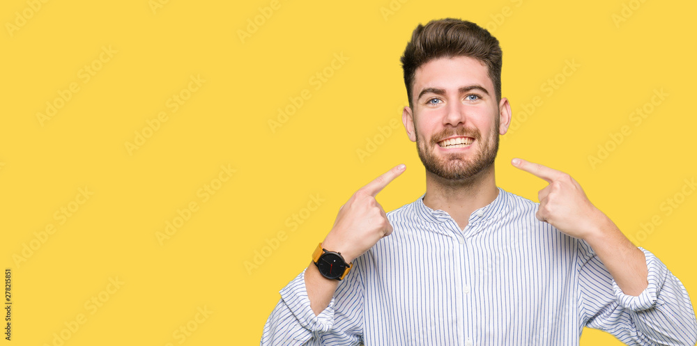 Young handsome man smiling confident showing and pointing with fingers teeth and mouth. Health concept. Young handsome man smiling confident showing and pointing with fingers teeth and mouth. Health concept.