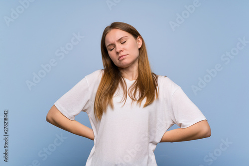 Young woman over blue wall suffering from backache for having made an effort