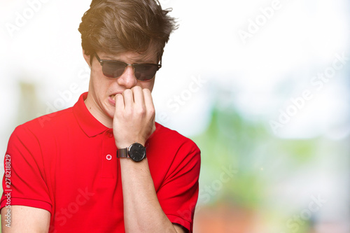 Young handsome man wearing sunglasses over isolated background looking stressed and nervous with hands on mouth biting nails. Anxiety problem.