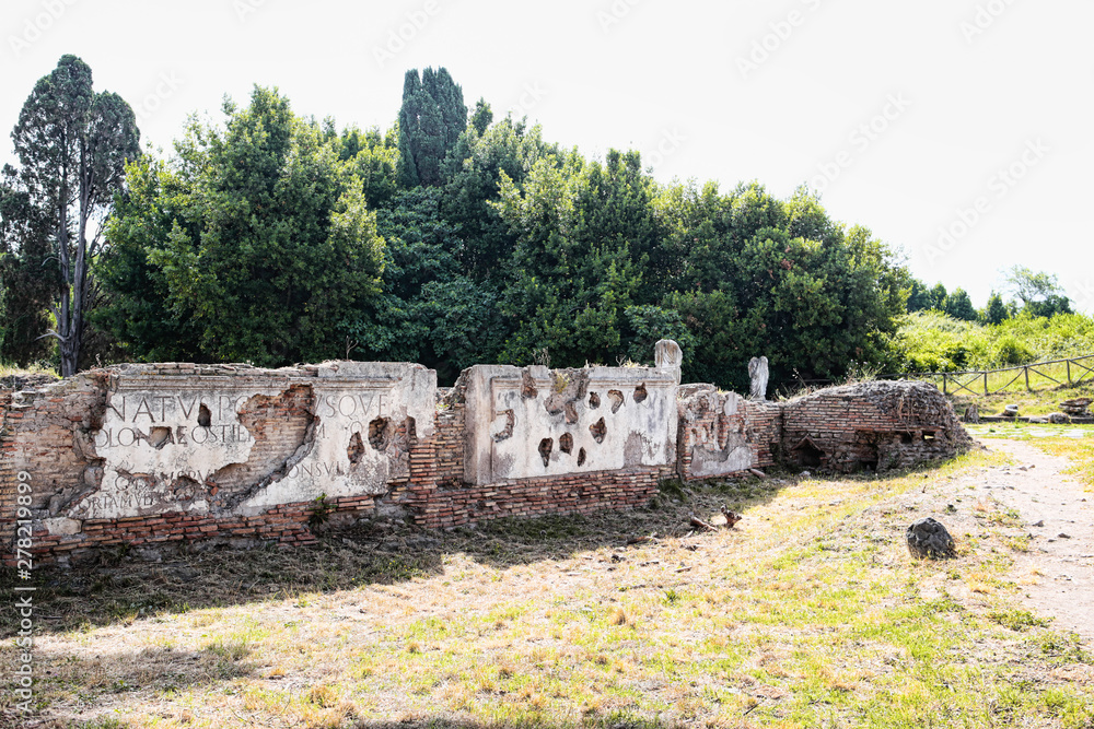 Roman Archaeological excavations of Ostia Antica with fragments of ancient latin inscriptions placed on the attic of Porta Romana