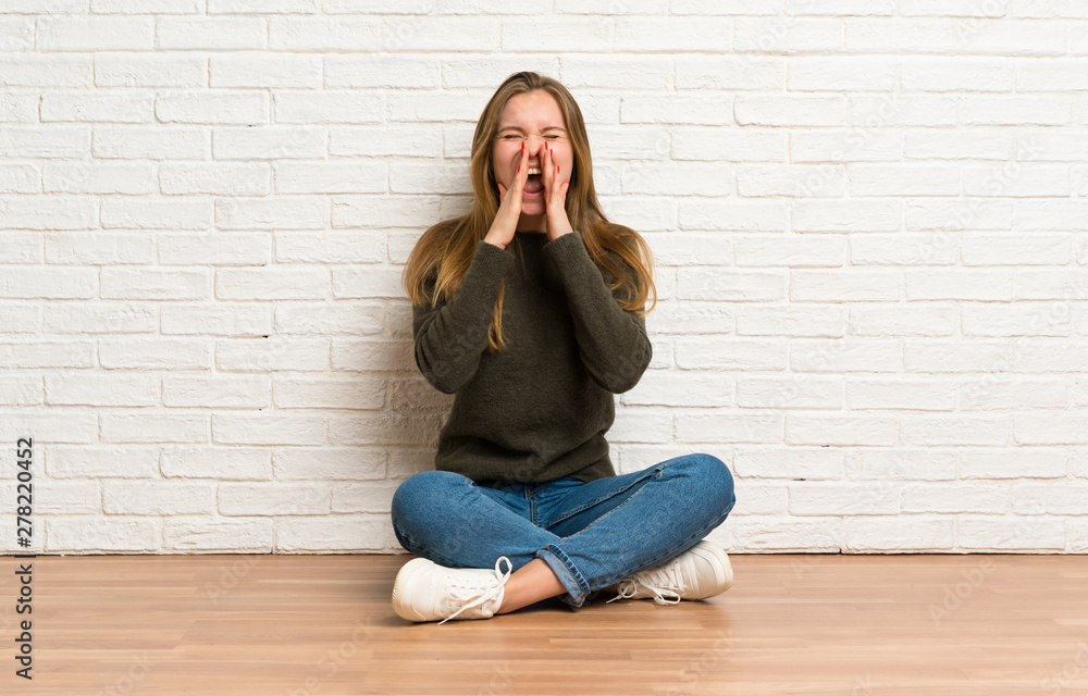 Young woman sitting on the floor shouting and announcing something Young woman sitting on the floor shouting and announcing something