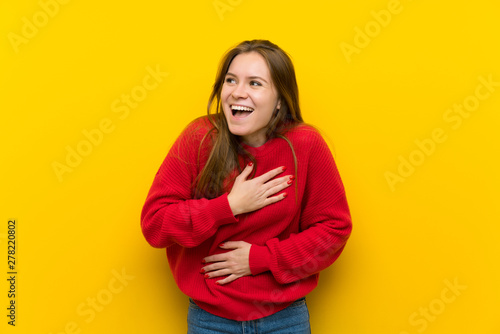 Young woman over yellow wall smiling a lot