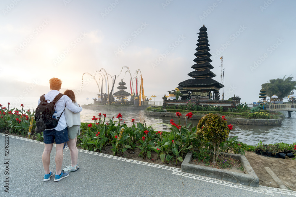 Unidentified lovers hugging and looking sunrise at Ulun Danu Beratan Temple, Bali, Indonesia