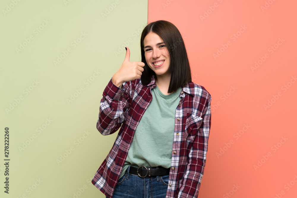 Young woman over isolated colorful wall with thumbs up because something good has happened Young woman over isolated colorful wall with thumbs up because something good has happened