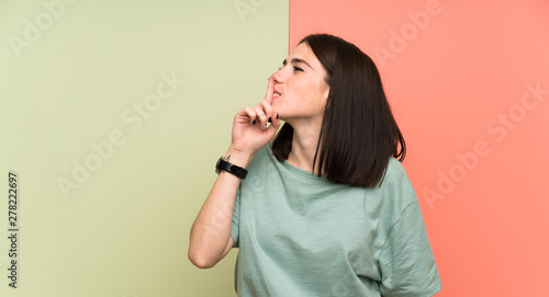 Young woman over isolated colorful wall doing silence gesture