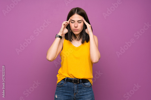 Young woman over isolated purple wall with headache