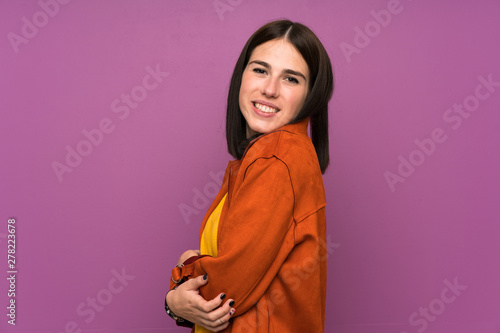 Young woman with a coat over isolated purple background laughing © luismolinero