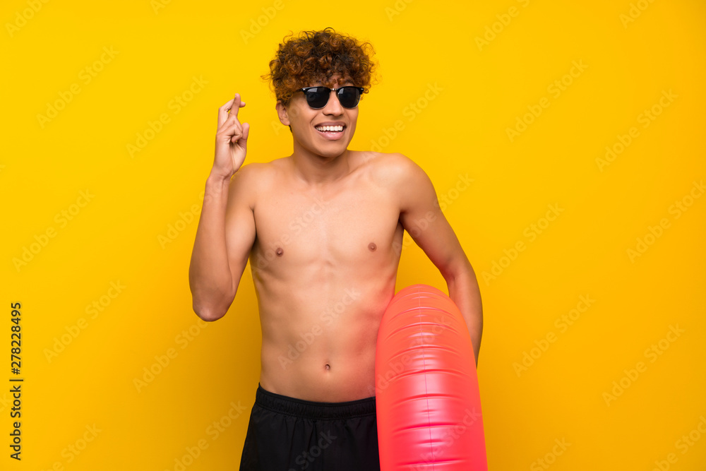 African american man over isolated purple wall with fingers crossing