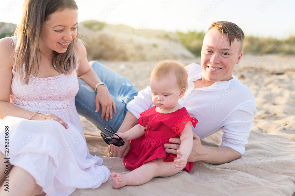 Fototapeta premium Family holiday near the sea. Father, mother and little daughter on beach.