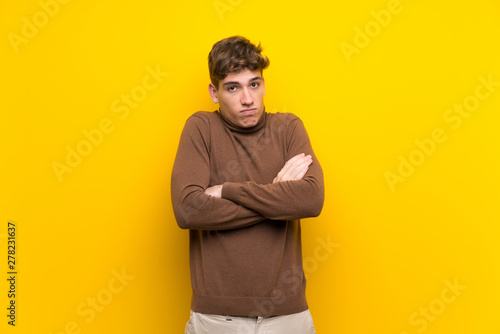 Handsome young man over isolated yellow background making doubts gesture while lifting the shoulders © luismolinero