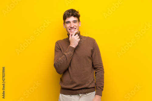 Handsome young man over isolated yellow background smiling