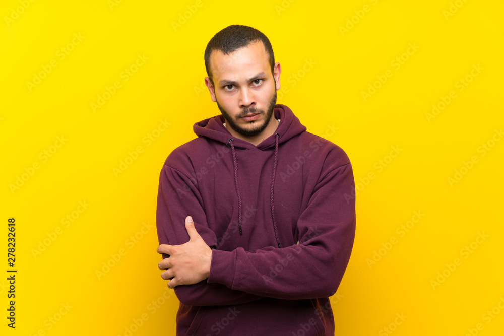 Fototapeta premium Colombian man with sweatshirt over yellow wall feeling upset