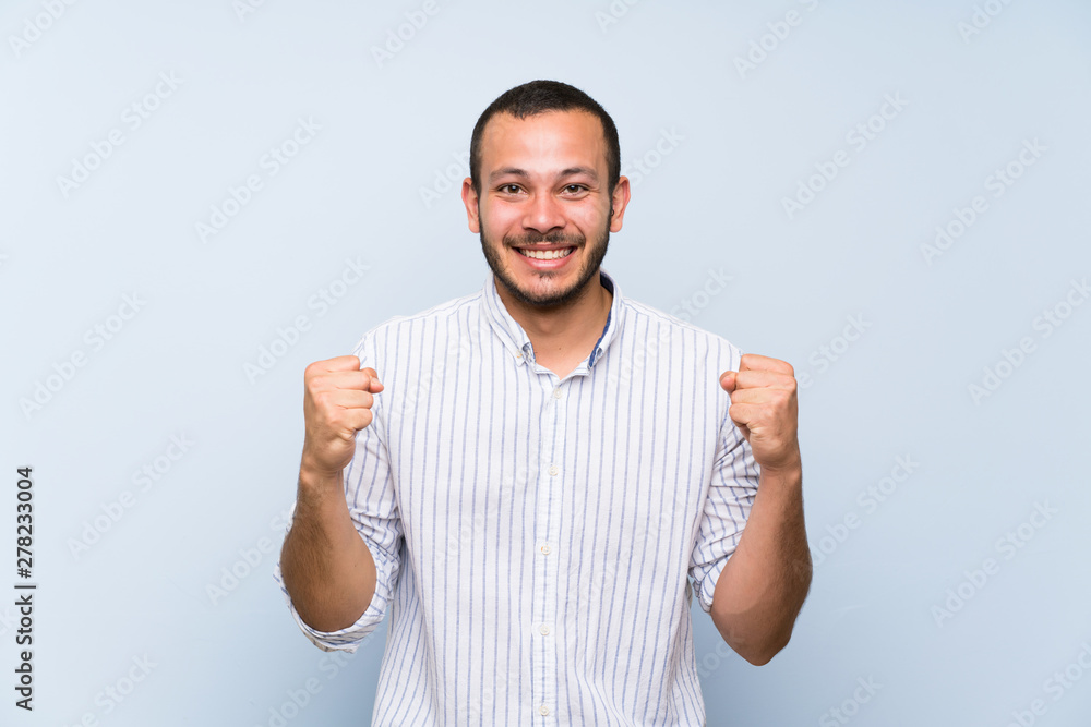 Fototapeta premium Colombian man over isolated blue wall celebrating a victory in winner position