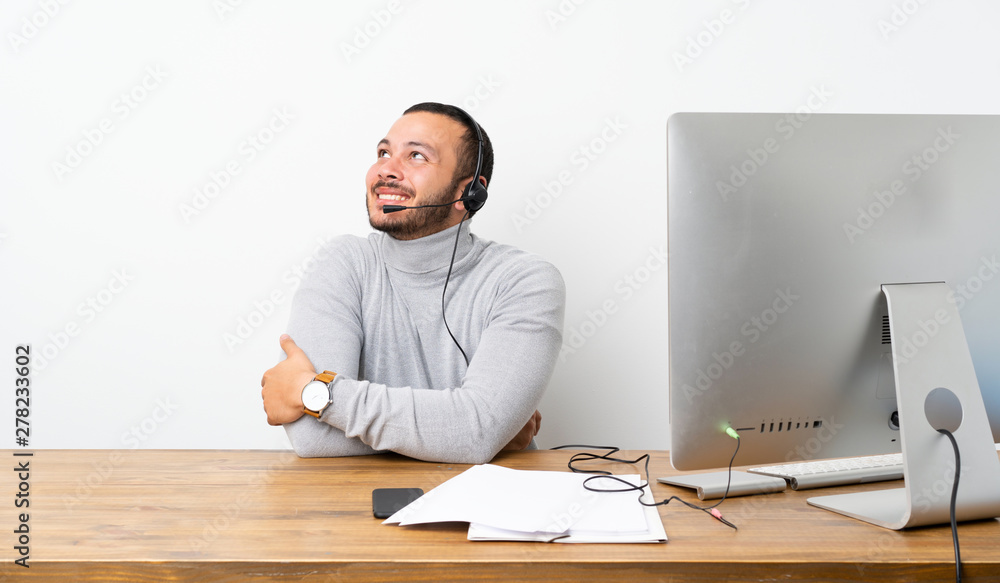 Telemarketer Colombian man looking up while smiling