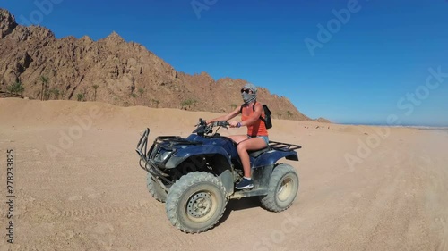 Sexy Woman is Riding a Quad Bike in the Desert of Egypt. Dynamic view in motion. photo