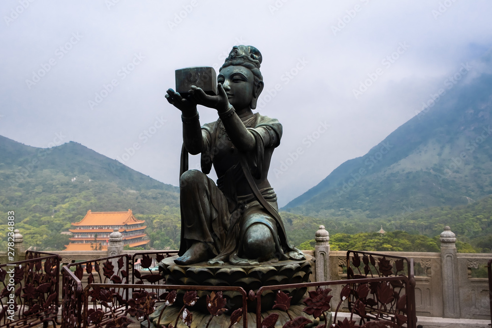 Black bronze metallic buddha statue with mountains and temple on background, HongKong