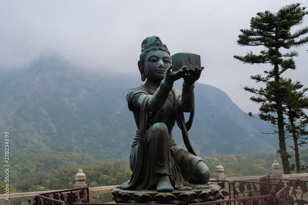 Black metallic buddha statue with mountains on background, HongKong