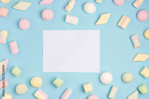 Blue paper background with marshmallow and notepad. Place for your text. Cozy sweet background