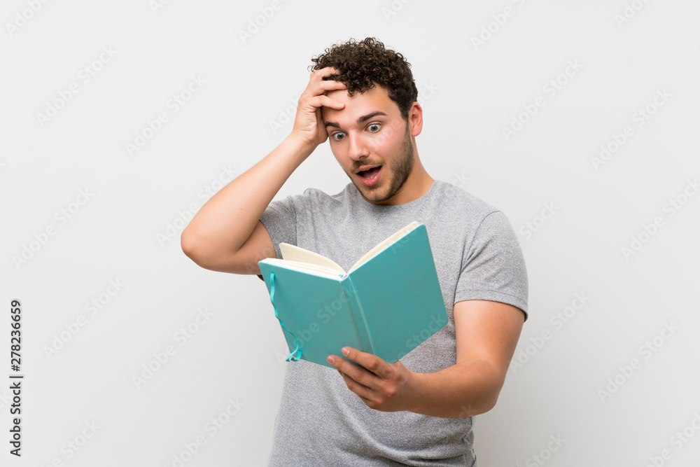 Man with curly hair over isolated wall holding and reading a book Man with curly hair over isolated wall holding and reading a book