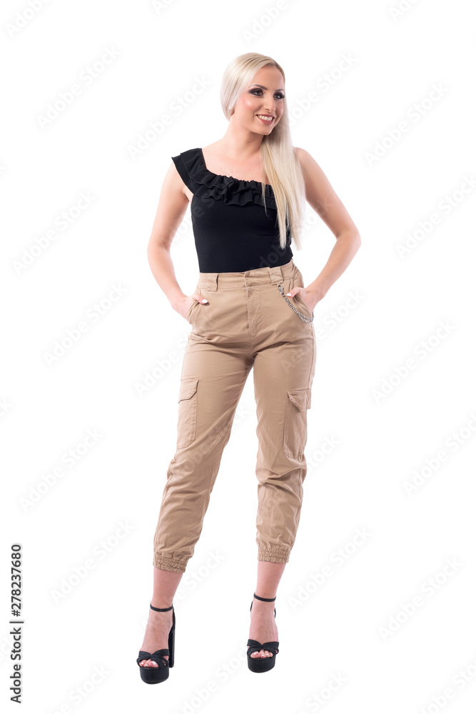 Luxury street style look fashion blonde woman in military trousers smiling and looking away. Full body isolated on white background. Luxury street style look fashion blonde woman in military trousers smiling and looking away. Full body isolated on white background.