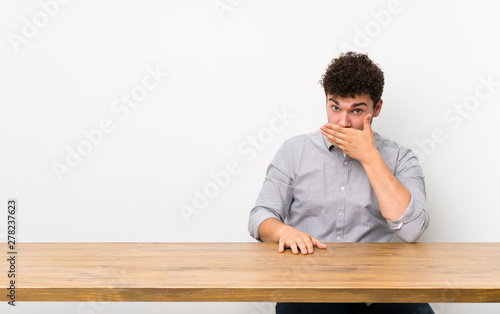 Young man with a table covering mouth with hands © luismolinero