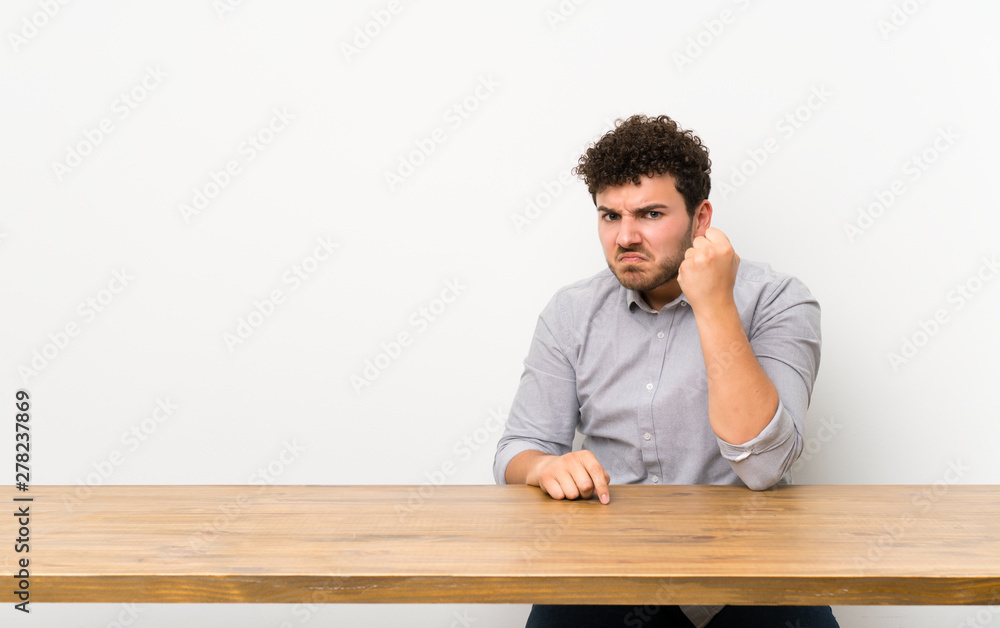 Young man with a table with angry gesture Young man with a table with angry gesture