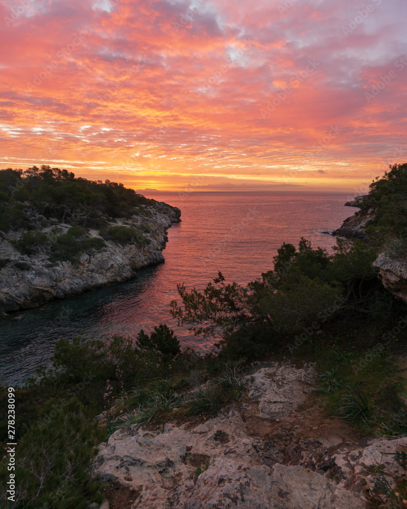 Sunrise with orange sky and water from a small bay in Mallorca, Spain. 