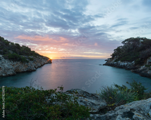Sunrise from a small bay with orange and yellow sky in Mallorca, Spain. 