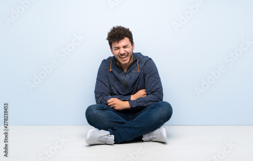 Young man sitting on the floor smiling a lot © luismolinero