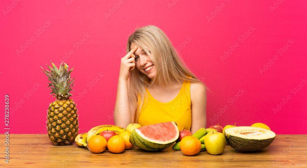 Young blonde woman with lots of fruits laughing Young blonde woman with lots of fruits laughing