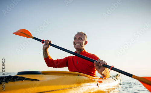Smiling senior man paddling kayak
